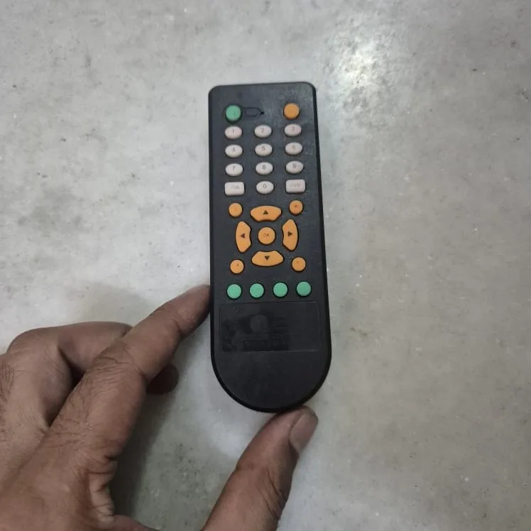 Vintage Black TV Remote Control with Orange and Green Buttons — Tech and Electronics prop for rent in Delhi NCR